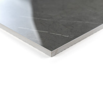 Eine polierte, dunkelgraue Fliese mit dezenten Adermustern liegt auf einer weißen Oberfläche und reflektiert sanftes Licht in ei