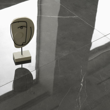 Ein skulpturaler Kopf auf einem Ständer wirft einen Schatten auf glatte, reflektierende graue Fliesen und suggeriert so einen mo