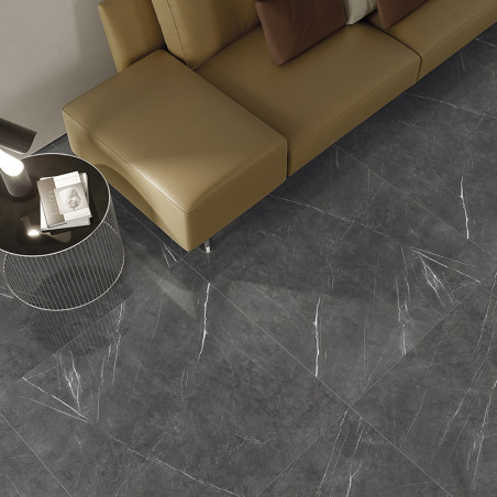 Graue Marmorfliesen mit weißen Maserungen bedecken den Boden, daneben ein braunes Sofagarnitur und ein runder Beistelltisch mit 