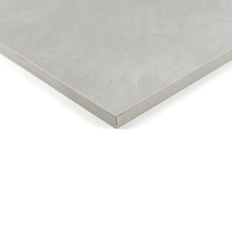 Un azulejo cuadrado, liso y gris descansa sobre un fondo blanco, mostrando su borde limpio y nítido en un ambiente minimalista.