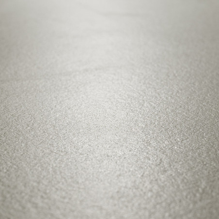 Eine strukturierte, hellgraue Fliesenoberfläche wirkt glatt und dennoch dezent körnig und reflektiert sanftes Licht in einer neu