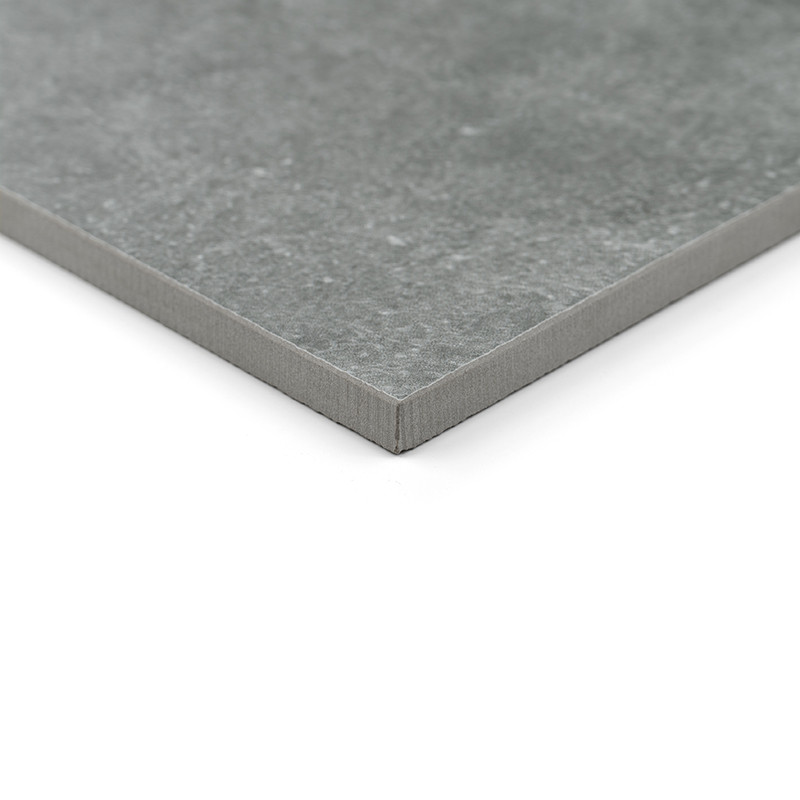 Un carreau de céramique carré gris repose sur une surface blanche, mettant en valeur un motif subtilement texturé avec un bord l