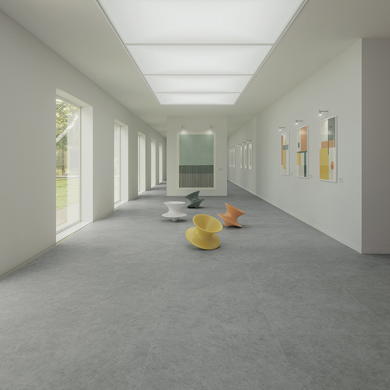 As cadeiras estão espalhadas por um corredor longo e cheio de luz, com grandes janelas e obras de arte emolduradas revestindo as