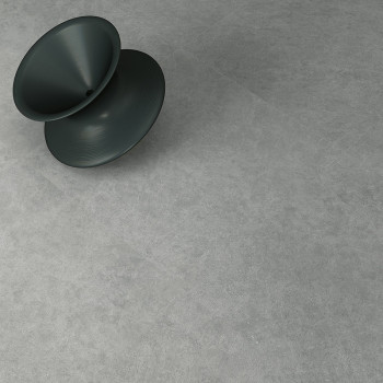 Ein dunkler, konischer Hocker steht diagonal auf einer glatten, hellgrauen Steinoberfläche und suggeriert einen Innenraum mit mi