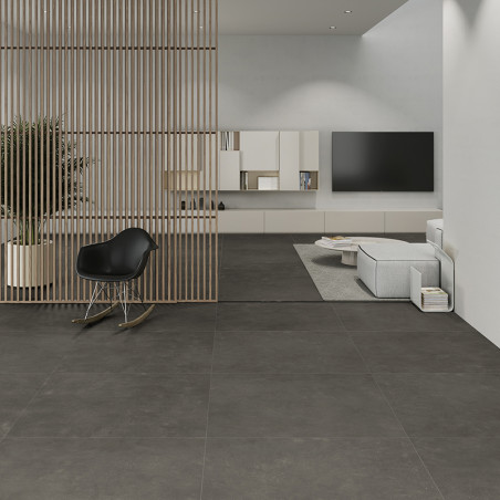 Dunkelgraue Fliesen bedecken einen modernen Wohnraum und trennen einen eleganten Loungebereich mit einem schwarzen Stuhl und ein