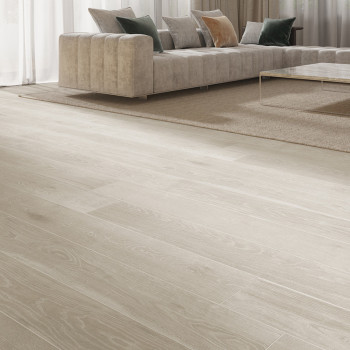 Des planches de parquet s'étendent dans un salon moderne, menant à un canapé sectionnel moelleux et à une table basse en verre s