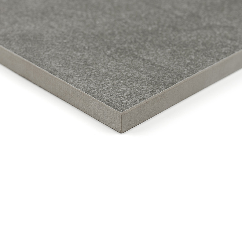 A square, gray ceramic tile with a smooth surface rests against a white background, highlighting its thickness and clean edges.