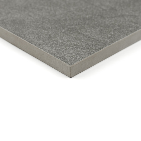 Un carreau de céramique carré gris à la surface lisse repose sur un fond blanc, soulignant son épaisseur et ses bords nets.