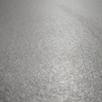 Une surface de carrelage gris clair texturée reflète subtilement la lumière, créant un effet chatoyant sur son motif légèrement 