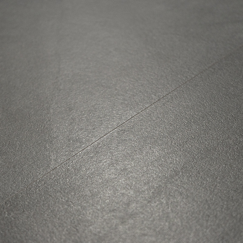 A smooth, matte gray tile surface is lying flat, showing a subtle seam line running diagonally, set in a minimalistic context.