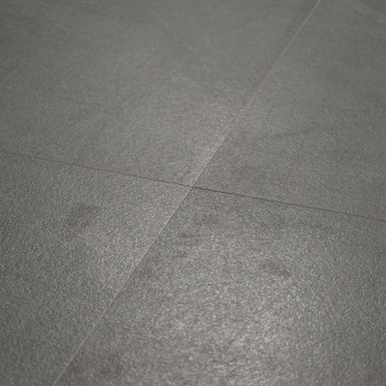 Un carrelage de sol gris mat repose à plat, entrecoupé de lignes de coulis subtiles, créant une surface lisse et uniforme dans u