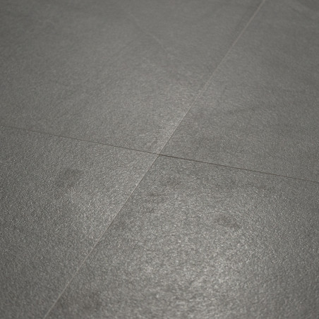 Un carrelage de sol gris mat repose à plat, entrecoupé de lignes de coulis subtiles, créant une surface lisse et uniforme dans u