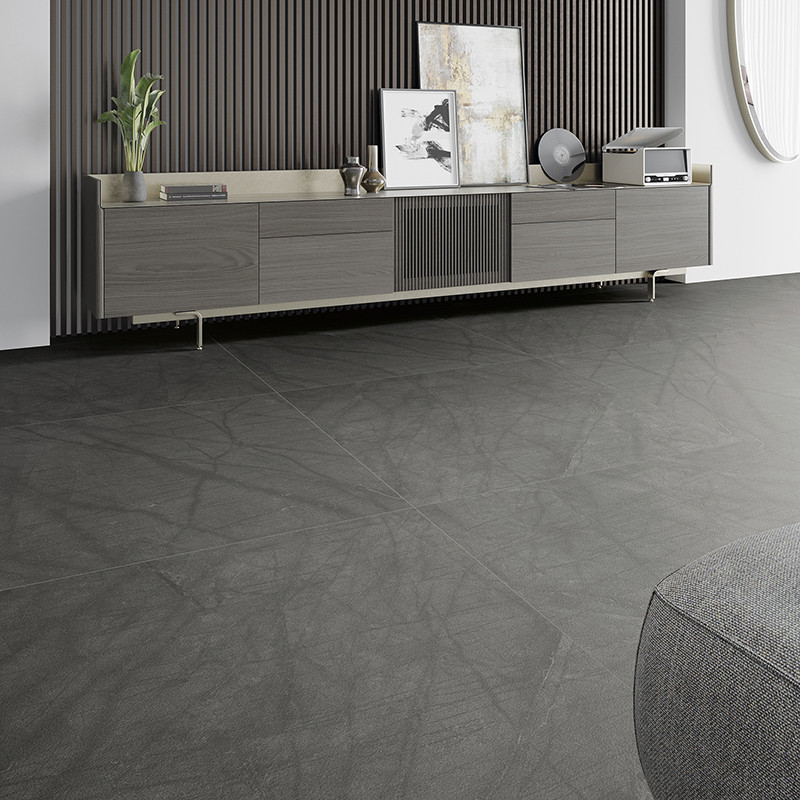 Un sol en carrelage gris aux motifs linéaires subtils s'étend dans un salon moderne. En arrière-plan, une armoire élégante conti