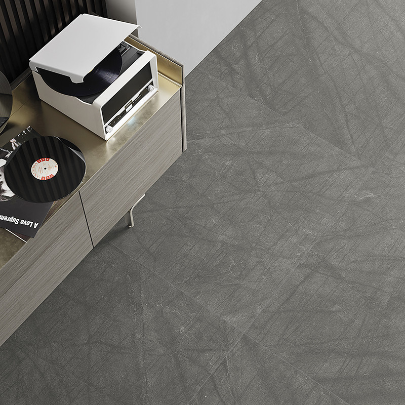 Gray floor tiles with subtle crosshatch patterns provide a modern, textured surface beside a wooden cabinet holding vinyl record