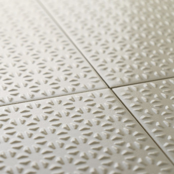 Strukturierte Keramikfliesen bilden ein sich wiederholendes Muster aus Sonnenstrahlen in sanftem Beige, die sauber in einem mit 