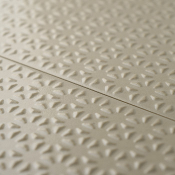 Beigefarbene Fliesen zeichnen sich durch ein sich wiederholendes erhabenes Blumenmuster aus, das für Struktur und Tiefe sorgt. D