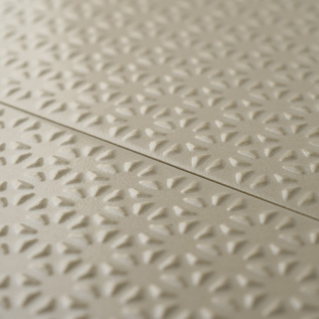 Beigefarbene Fliesen zeichnen sich durch ein sich wiederholendes erhabenes Blumenmuster aus, das für Struktur und Tiefe sorgt. D