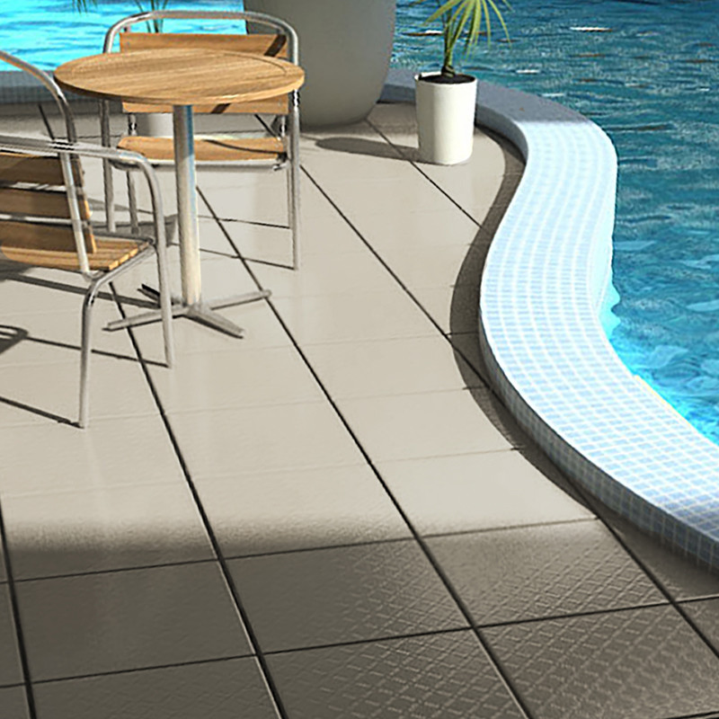 Een ronde houten tafel met metalen stoelen staat op beige tegels naast een gebogen zwembad, dat zonlicht reflecteert en wordt be