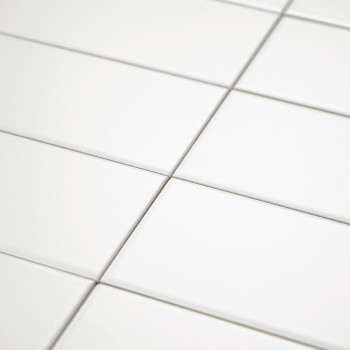 White ceramic tiles are evenly arranged in a grid pattern, creating a clean and seamless surface with subtle grout lines in well