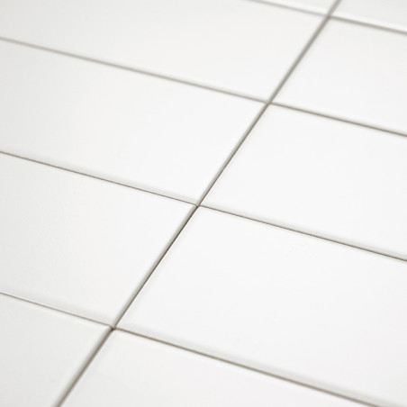 Les carreaux de céramique blanche sont disposés uniformément selon un motif en grille, créant une surface propre et homogène ave