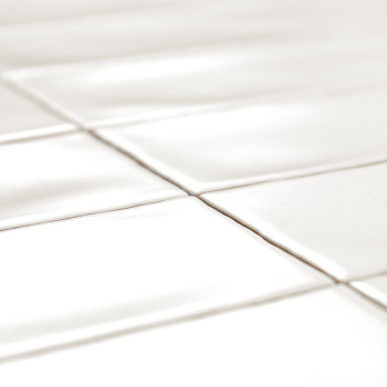 White rectangular tiles are laid out in a grid pattern, casting soft shadows due to light reflection, creating a clean and minim
