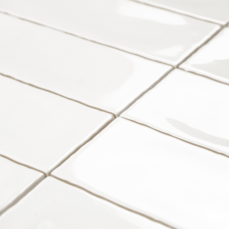 Les carreaux rectangulaires blancs sont alignés en quinconce, réfléchissant la lumière sur une surface lisse et brillante avec u