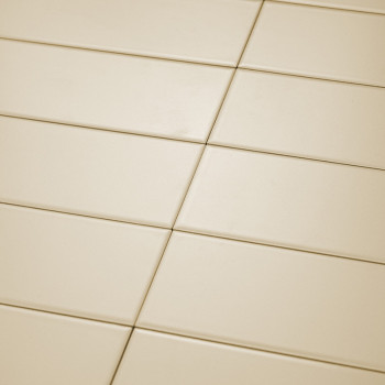 Cream-colored rectangular tiles are neatly arranged in a diagonal grid pattern. The smooth surface reflects light uniformly unde
