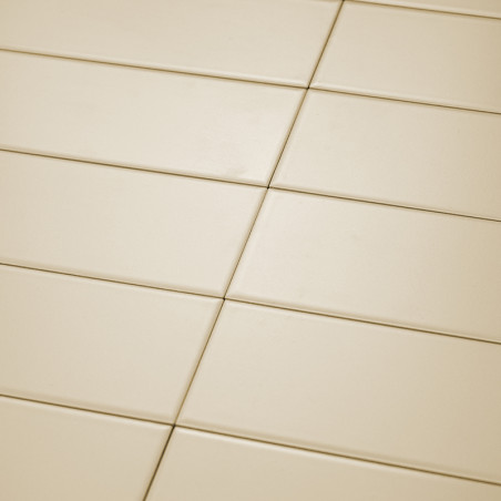 Cream-colored rectangular tiles are neatly arranged in a diagonal grid pattern. The smooth surface reflects light uniformly unde