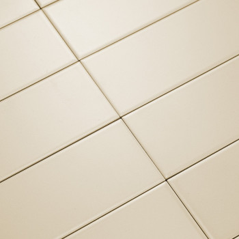 Cream-colored rectangular tiles lay diagonally, forming a grid pattern. The smooth surface reflects light, creating a clean, min