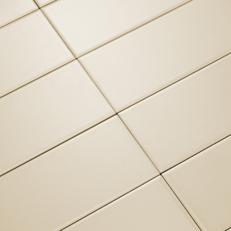 Cream-colored rectangular tiles lay diagonally, forming a grid pattern. The smooth surface reflects light, creating a clean, min