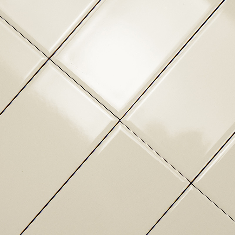 Cremefarbene Fliesen, die diagonal angeordnet sind, bilden ein Gittermuster und erzeugen eine glatte, reflektierende Oberfläche,
