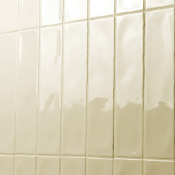 Rechteckige, glänzende Fliesen sind in einem Gittermuster an einer Wand angeordnet und reflektieren das Licht in einem Badezimme