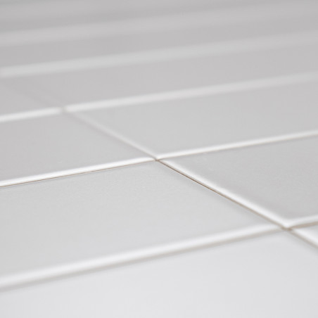 Weiße Keramikfliesen sind gitterförmig angeordnet und bilden eine glatte Oberfläche. Die Beleuchtung betont ihr sauberes, glänze