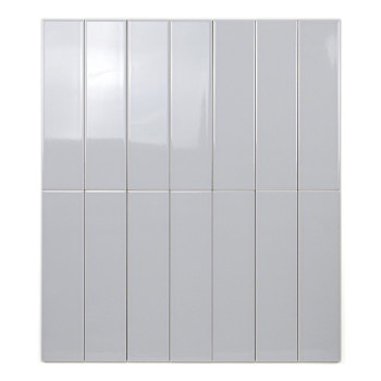 Um ladrilho retangular brilhante fica verticalmente, refletindo sutilmente a luz, colocado contra um fundo branco liso.