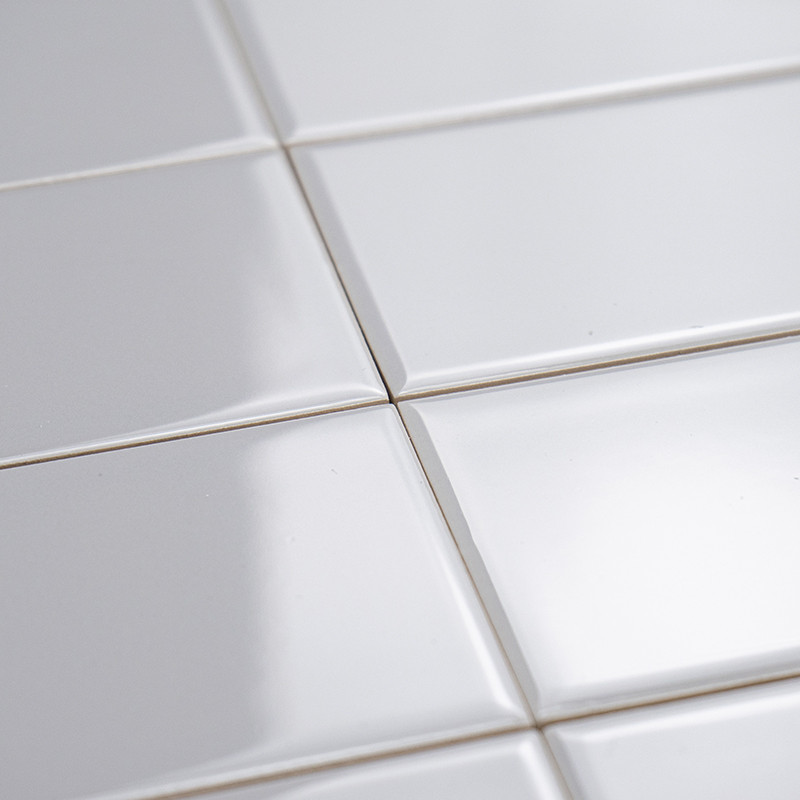 Les carreaux de céramique blancs et brillants sont plats et reflètent subtilement la lumière. Ils sont disposés selon un motif e
