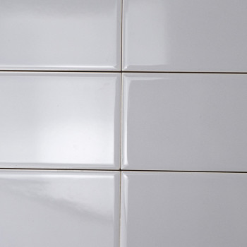 Les carreaux rectangulaires blancs sont alignés selon un motif de grille, créant une surface lisse et brillante sous un éclairag