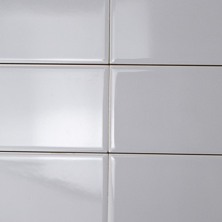 Les carreaux rectangulaires blancs sont alignés selon un motif de grille, créant une surface lisse et brillante sous un éclairag