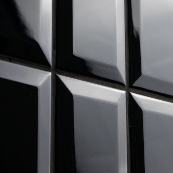 Glänzend schwarze Fliesen reflektieren das Licht und erzeugen einen glänzenden Spiegeleffekt. Sie sind in einem quadratischen Mu