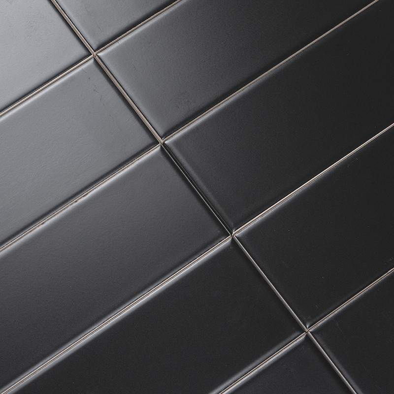 Los azulejos rectangulares negros están alineados diagonalmente en un patrón de cuadrícula, creando una superficie elegante y mo
