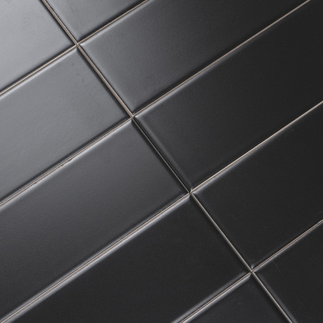 Black rectangular tiles are aligned diagonally in a grid pattern, creating a sleek, modern surface with subtle reflections.