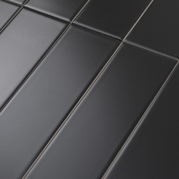 Los azulejos rectangulares mate oscuro están alineados en un patrón escalonado, creando una superficie moderna y perfecta. El co