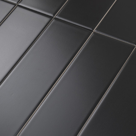Dark matte rectangular tiles are aligned in a staggered pattern, creating a seamless modern surface. The context is a grid-like 