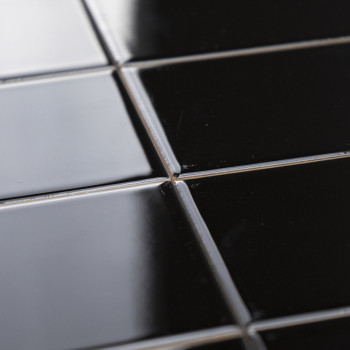 Les carreaux de céramique noirs brillants sont disposés selon un motif en grille, réfléchissant doucement la lumière, placés dan