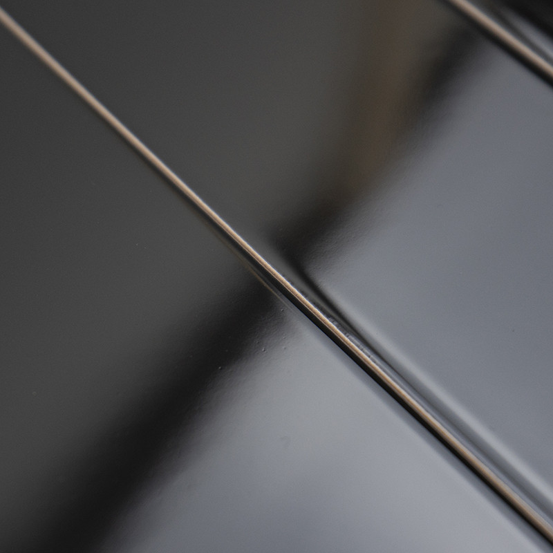 Ladrilhos pretos lisos e brilhantes ficam lado a lado, refletindo a luz sutilmente, criando uma superfície elegante e moderna.