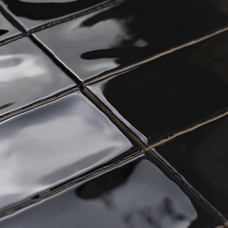 Los azulejos de cerámica negros brillantes reflejan la luz, dispuestos uniformemente en un patrón de cuadrícula. Los reflejos su