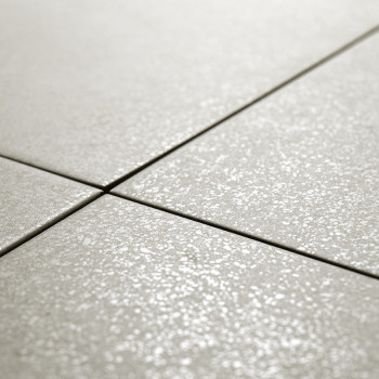 Keramische tegels, gerangschikt in een rasterpatroon, worden uitgelijnd op een vlak oppervlak. De tegels hebben een subtiele, ge