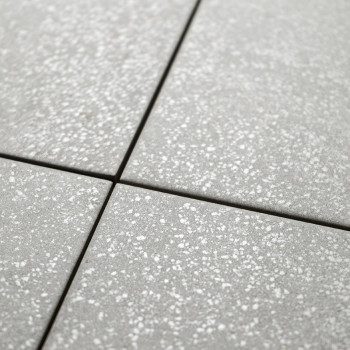 Graue quadratische Fliesen weisen ein dezentes gesprenkeltes Muster auf, wodurch eine strukturierte Oberfläche entsteht. Sie sin