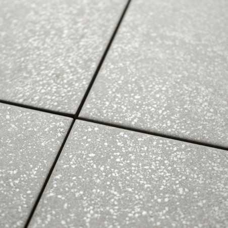Graue quadratische Fliesen weisen ein dezentes gesprenkeltes Muster auf, wodurch eine strukturierte Oberfläche entsteht. Sie sin