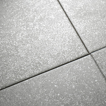 Graue, gesprenkelte Fliesen sind in einem Raster angeordnet und bilden eine nahtlose Oberfläche mit dezenten weißen Sprenkeln, d