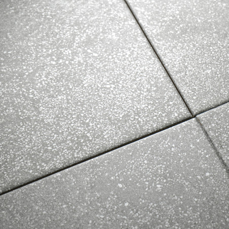 Graue, gesprenkelte Fliesen sind in einem Raster angeordnet und bilden eine nahtlose Oberfläche mit dezenten weißen Sprenkeln, d